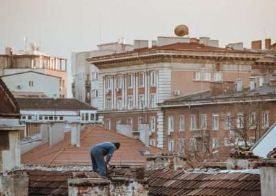 a man standing on top of a roof next to a tall building