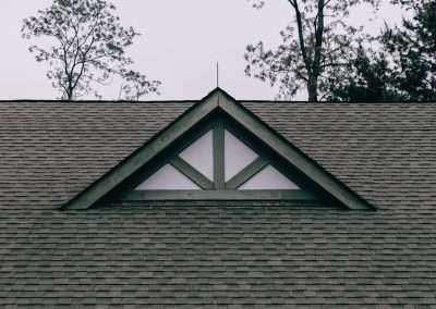 a roof with a triangle shaped window on top of it